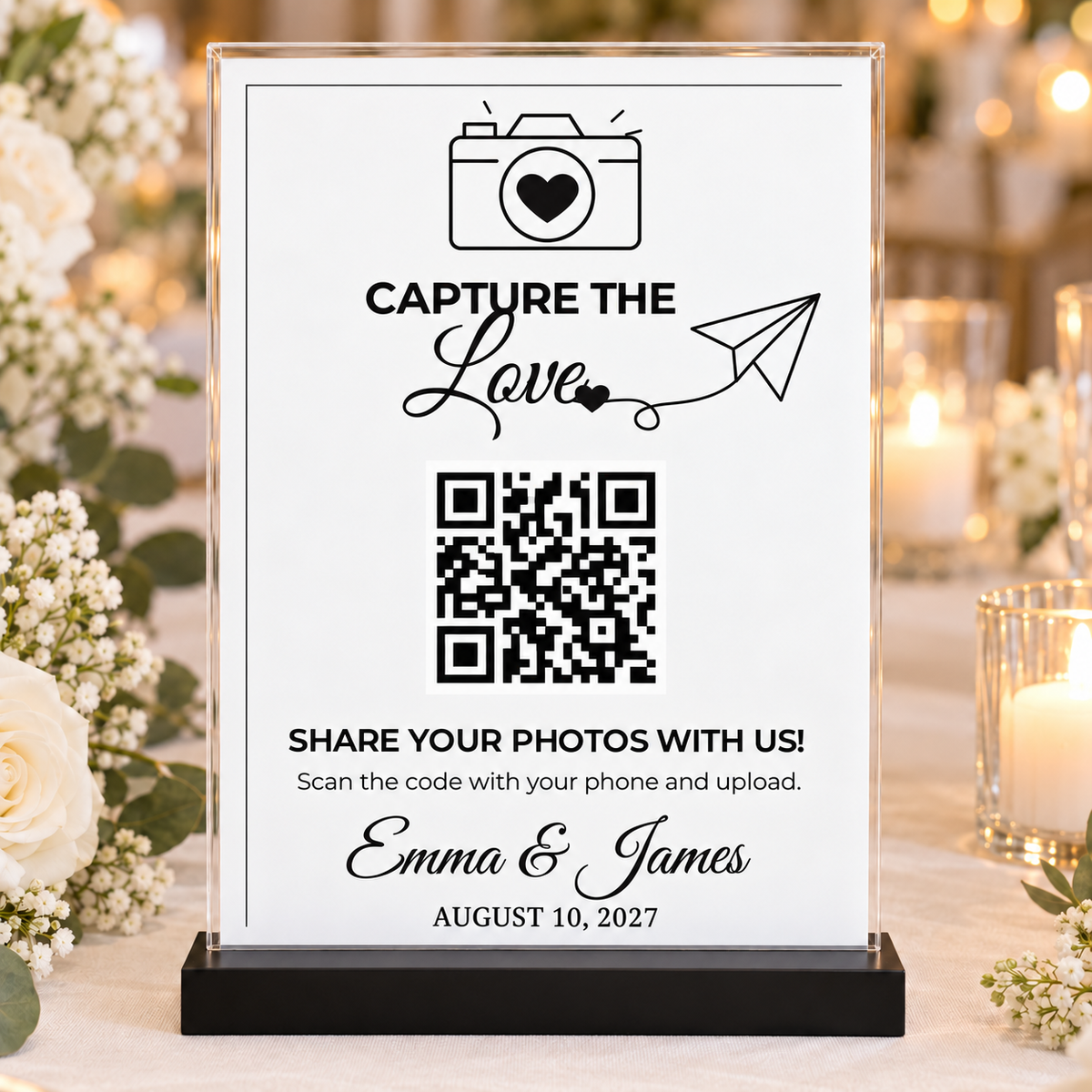 Black and white Capture the Love wedding QR sign with heart camera and paper plane, displayed in clear 5x7 acrylic holder with black base