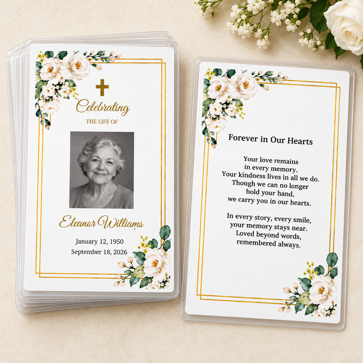Stack of personalized white rose and gold laminated memorial prayer cards beside the Forever in Our Hearts back